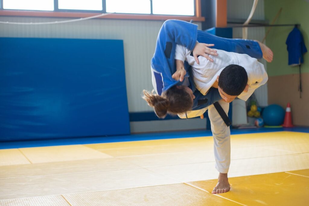pexels-photo-6765024 Two judokas practicing a powerful throw during judo training indoors on tatami mats.